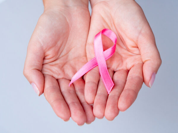 close-up-hands-holding-pink-ribbon-